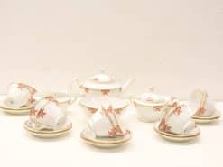 Elegant porcelain tea set with red flowers and gold trim, perfect for any occasion.