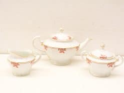 Elegant porcelain tea set with gold accents, featuring teapot, creamer, and sugar bowl.