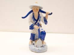 Traditional Chinese porcelain worker figurine, kneeling with shovel, celebrating agricultural heritage and craftsmanship.