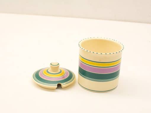 Vintage striped container with lid for storage or decorative use, featuring warm colors.