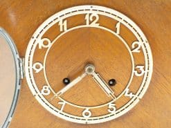 Elegant vintage wooden table clock with classic white face and warm wooden backdrop.