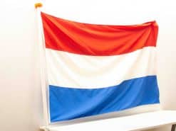 Vibrant Dutch flag with red, white, and blue stripes, proudly displayed on a pole.