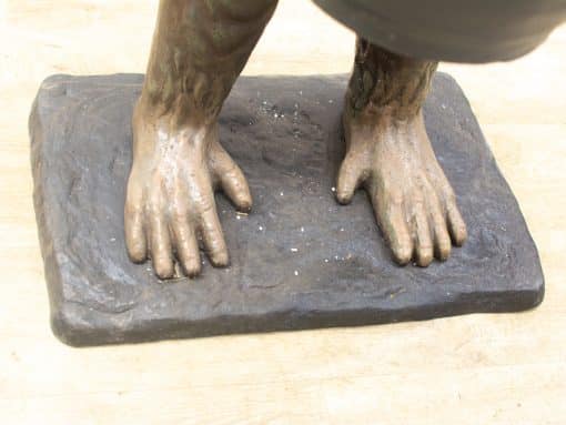 Dynamic bronze foot sculpture showcasing intricate details and realistic textures on a rugged base.