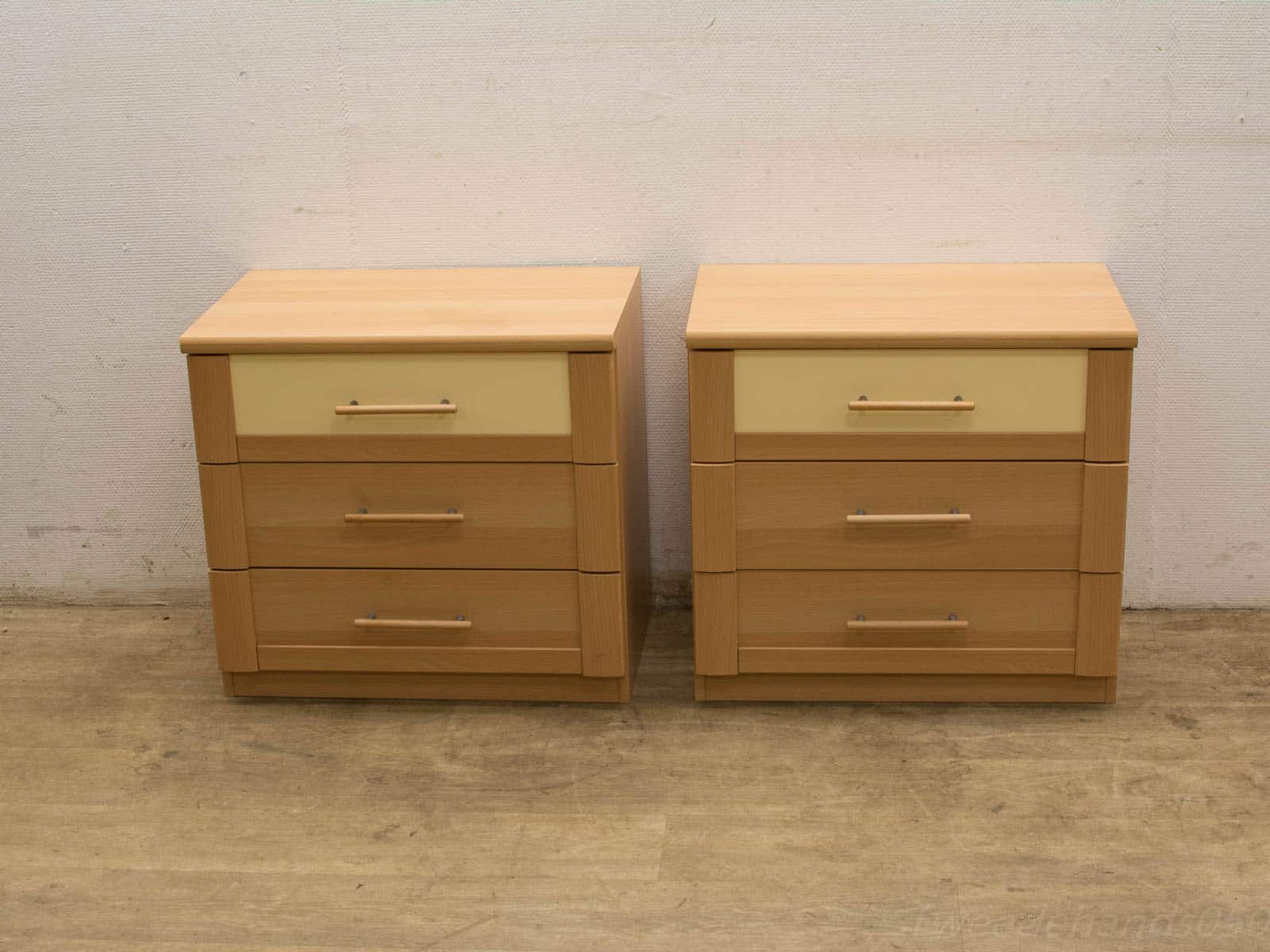 Minimalist light wood bedside tables with cream accents and metallic handles for modern decor.