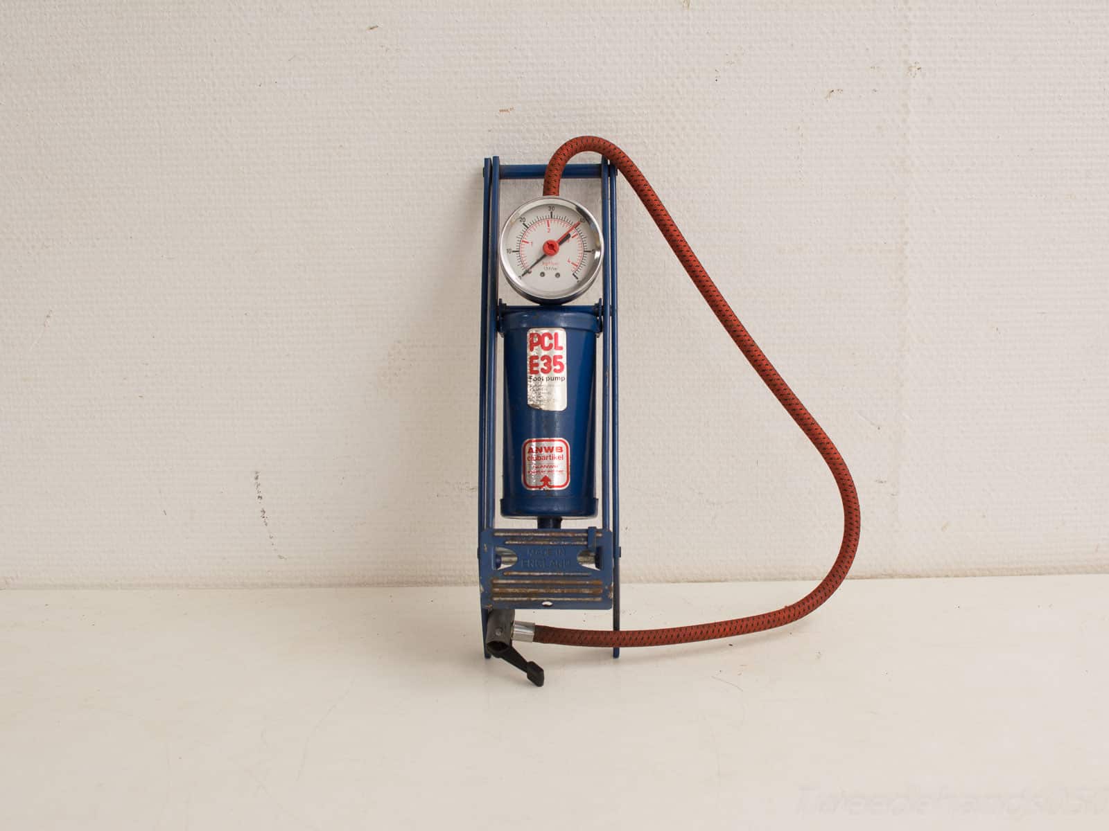 Vintage blue tire pressure gauge and inflator with red hose, perfect for automotive enthusiasts.