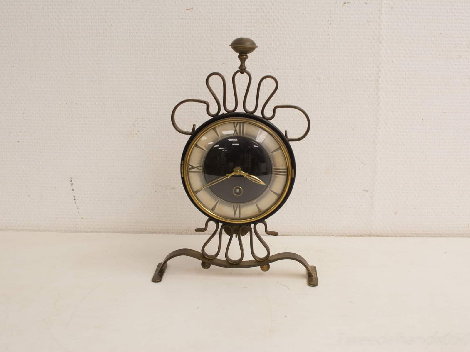 Elegant vintage clock with brass accents and Roman numerals on a black face. Timeless decor.