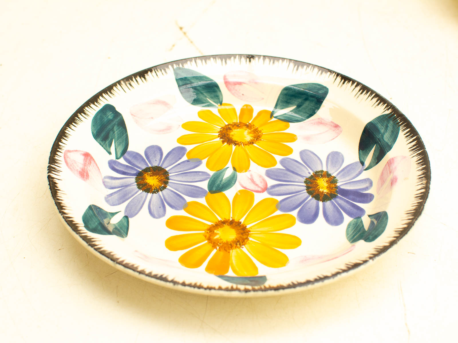 Charming vintage floral plate with yellow daisies and purple flowers, perfect for decor or collection.