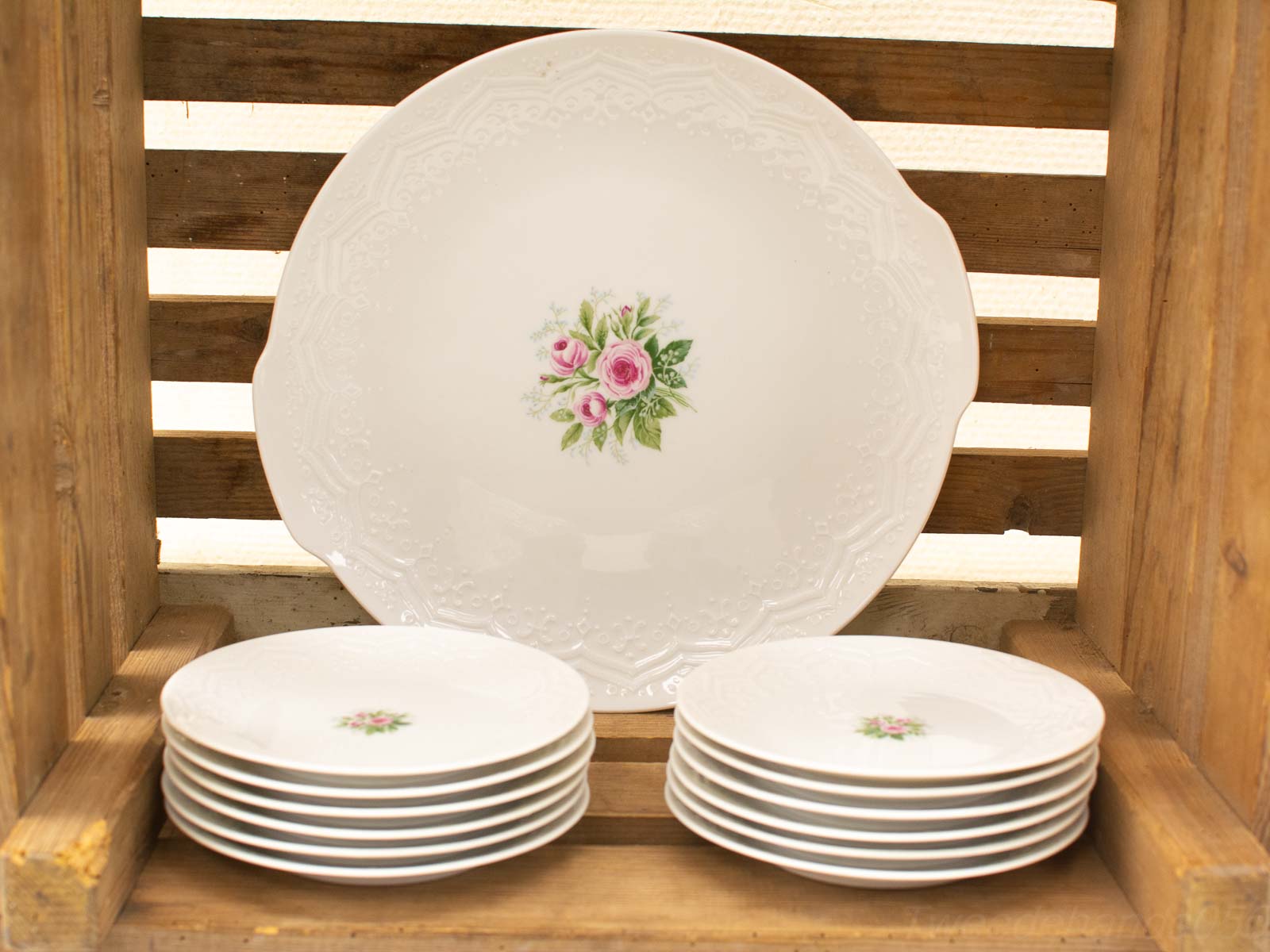 Charming porcelain dining set with floral designs, elegantly arranged in a rustic wooden crate.