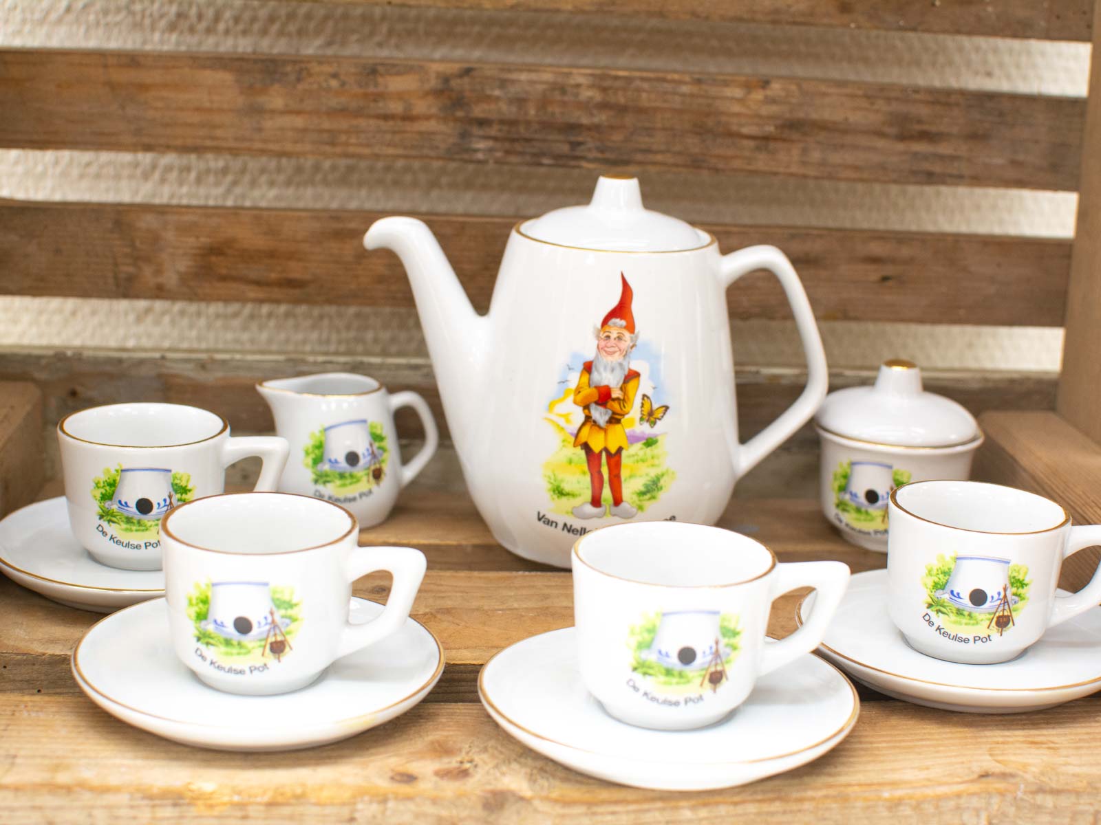 Whimsical vintage gnome tea set on rustic shelf, perfect for cozy gatherings and decor.