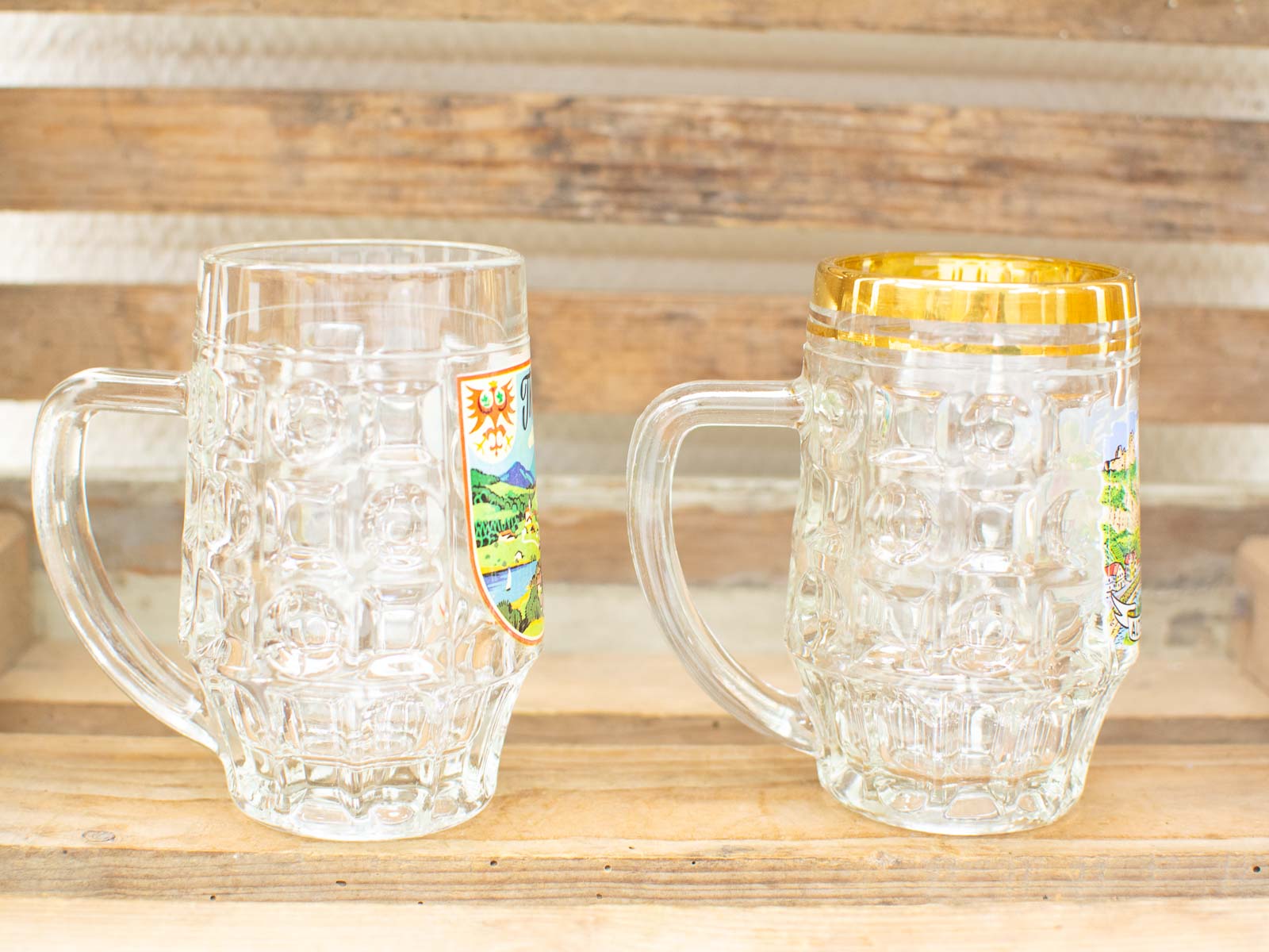 Textured glass beer mugs with unique emblems on rustic wood, perfect for festive celebrations.