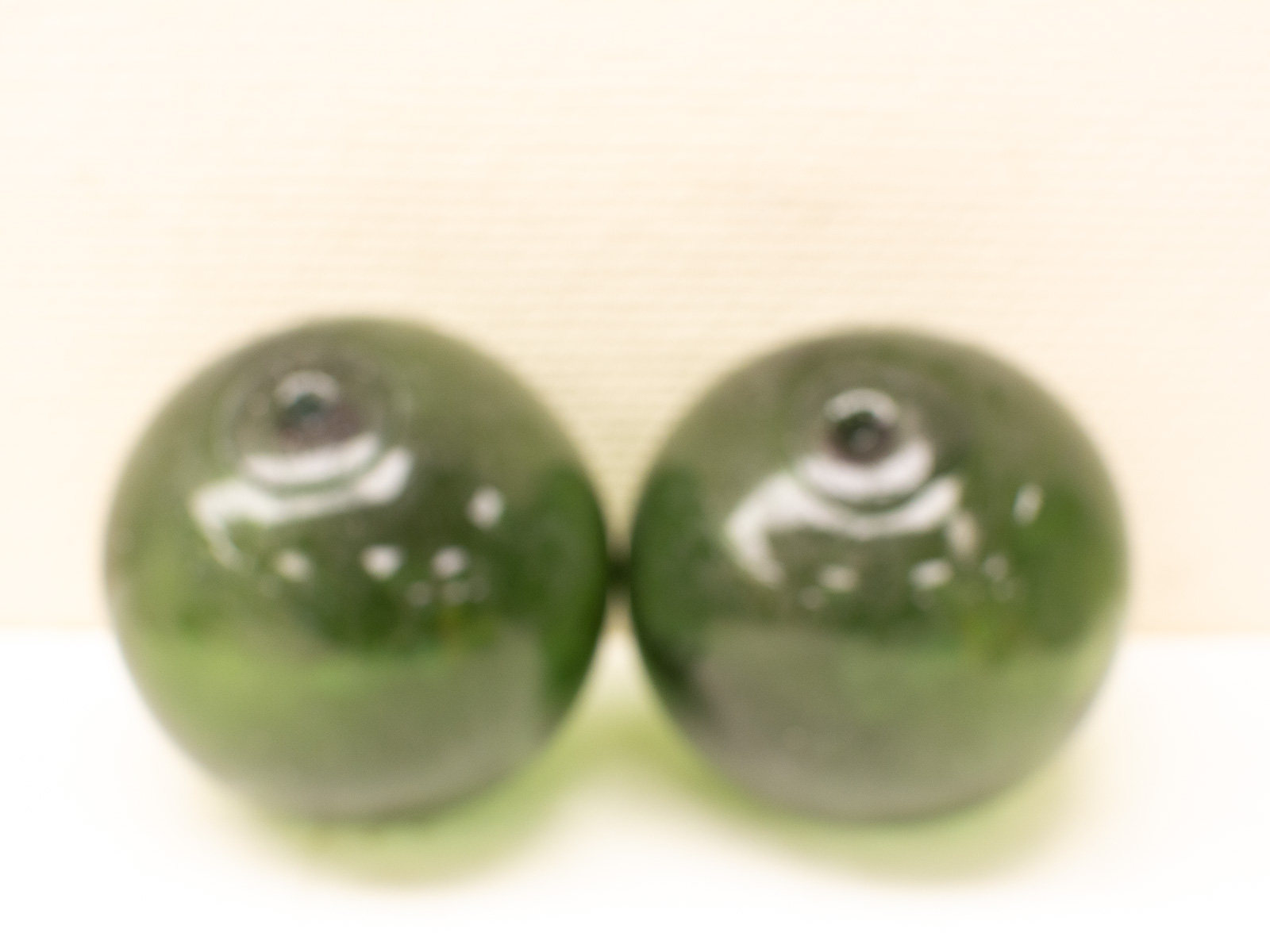 Glossy green spheres in a minimalist setting, evoking depth and intrigue.