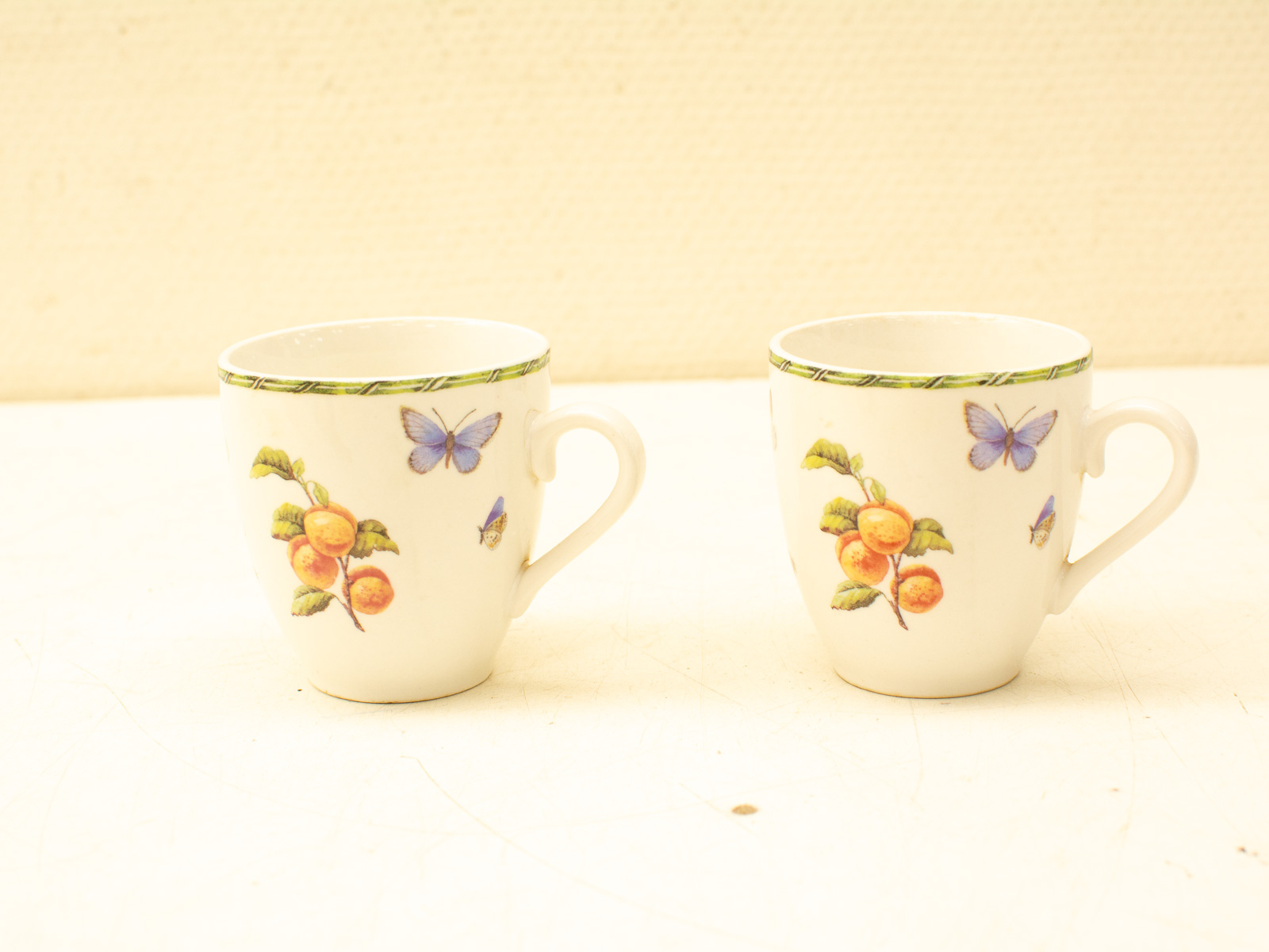 Charming vintage ceramic mugs with floral and butterfly designs for a cozy tea experience.