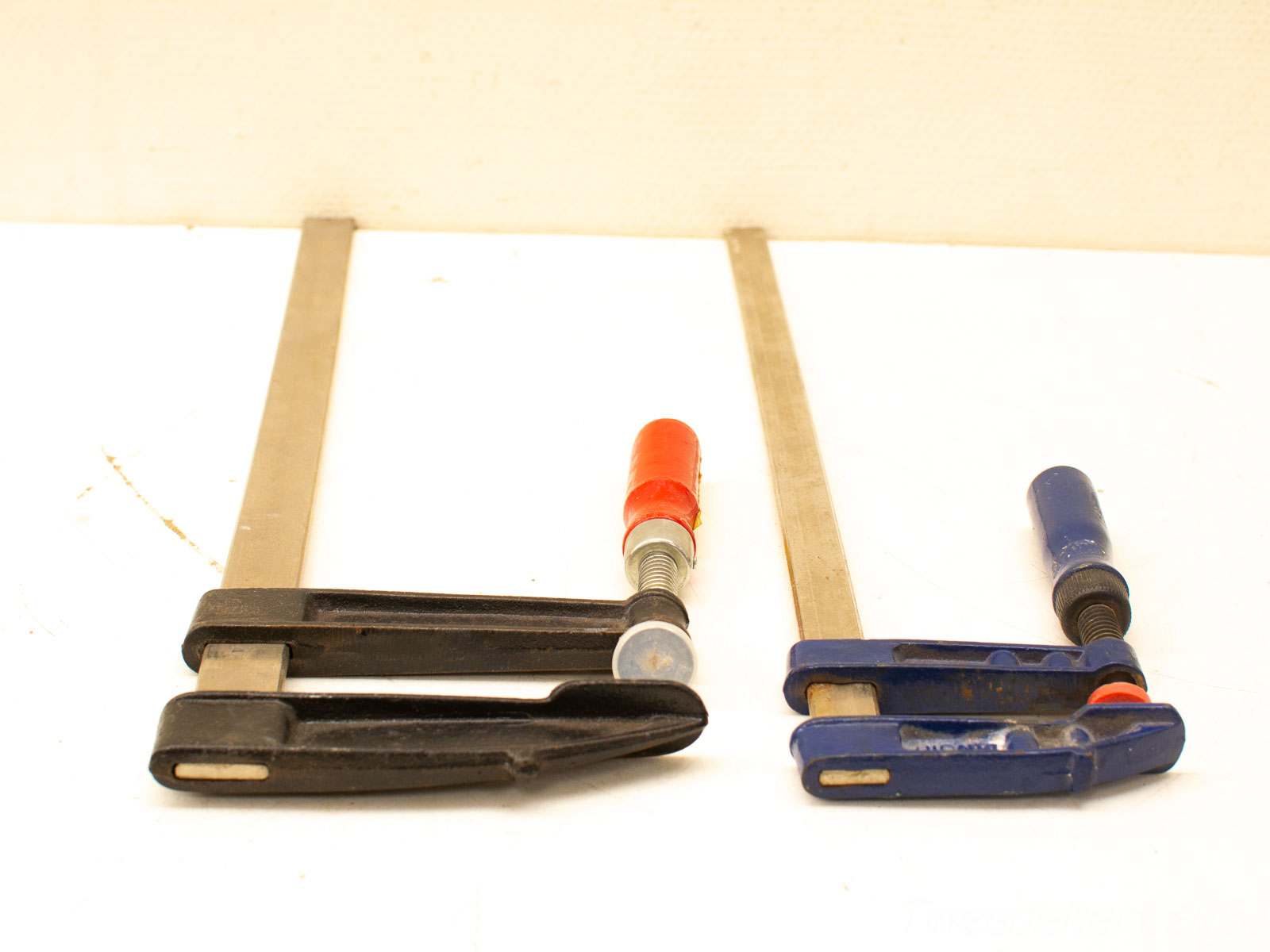 Versatile vintage clamps for woodworking: a sturdy black bar clamp and a compact blue C-clamp.