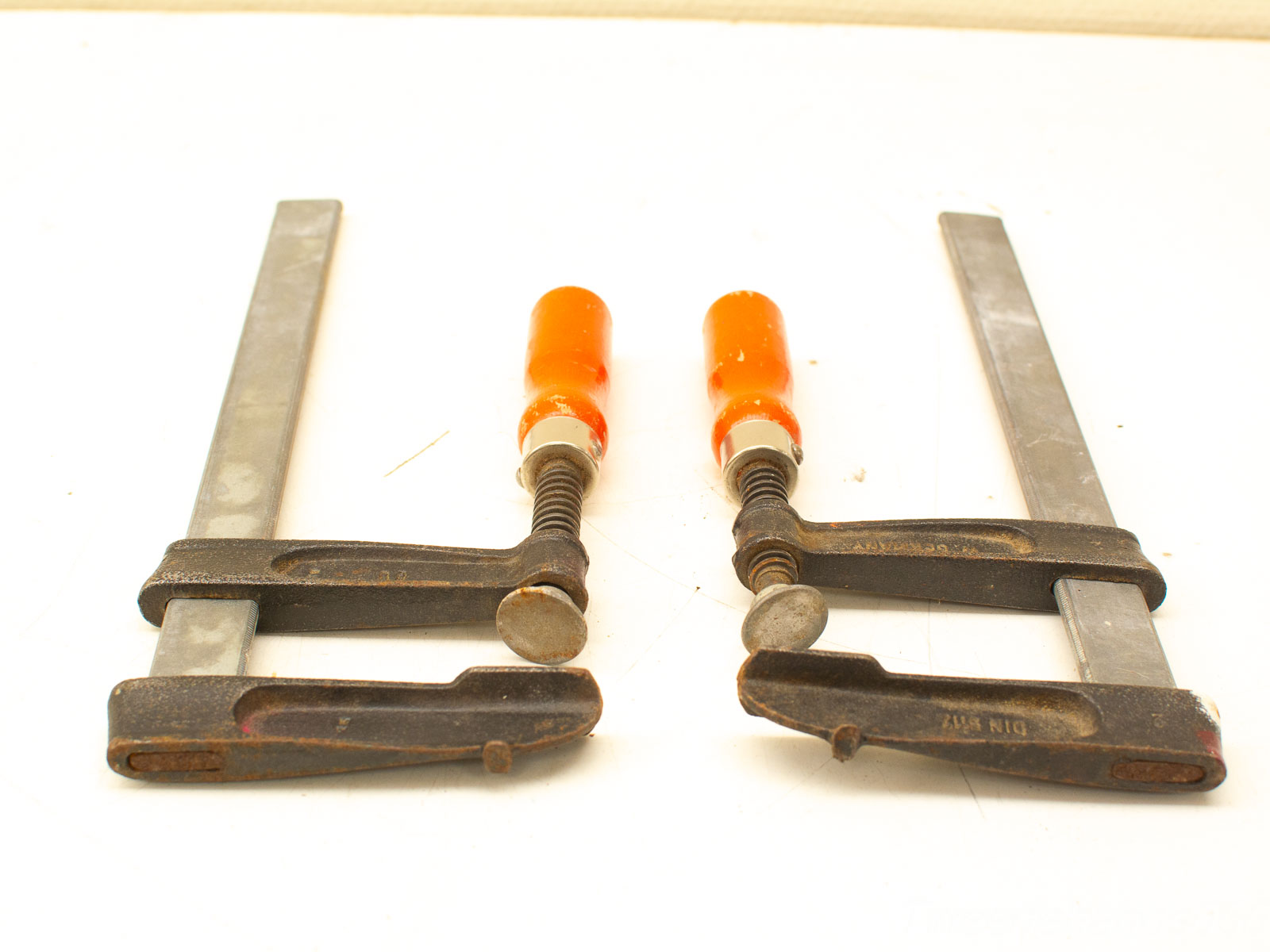 Identical parallel clamps with orange handles for woodworking and metalworking projects.