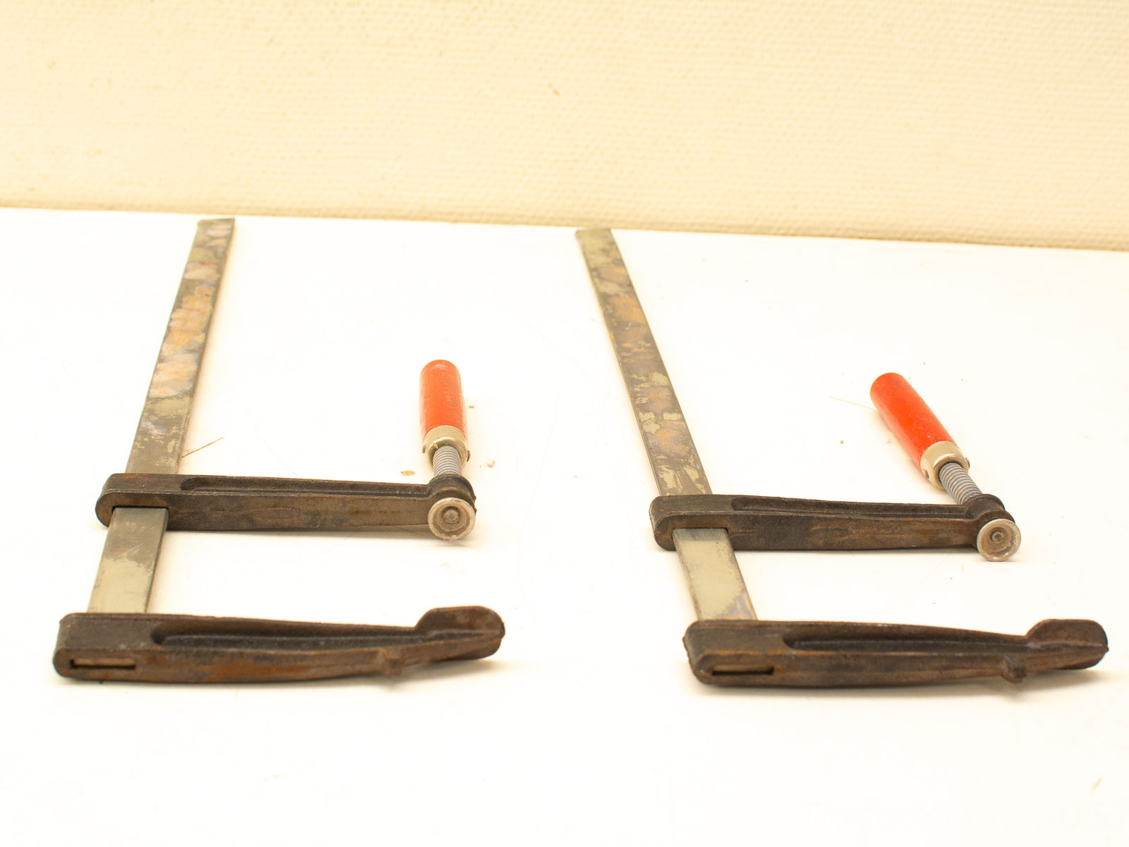 Vintage metal clamps with orange handles, showcasing reliability and character for woodworking enthusiasts.