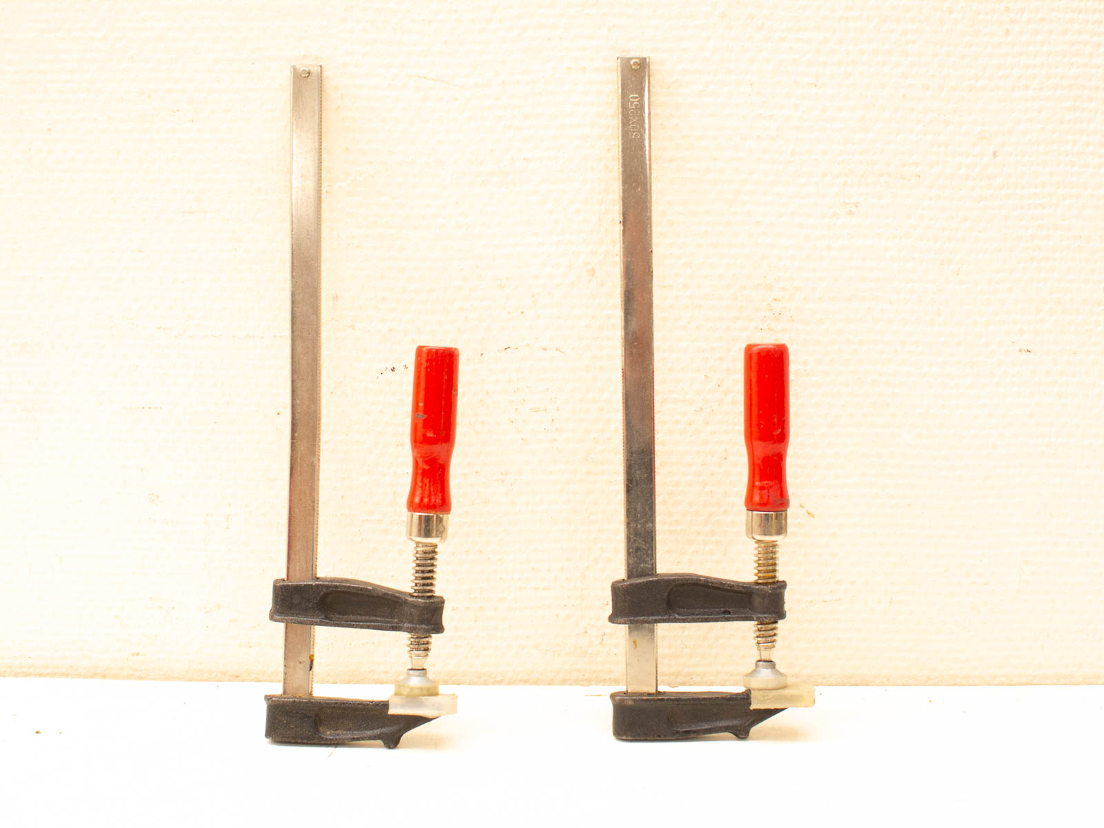 Durable vintage clamps with red handles for woodworking and metalworking projects.