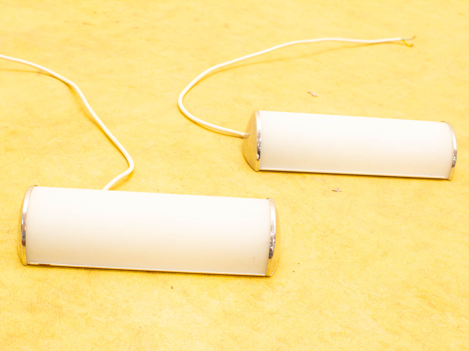 Sleek white cylindrical lamps on a vibrant yellow background, perfect for modern interiors.