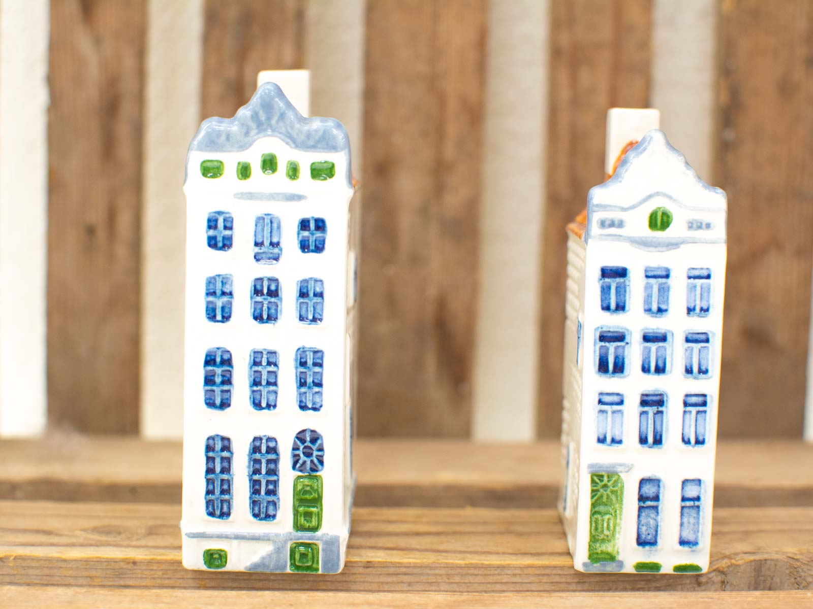 Charming vintage ceramic buildings with colorful details on rustic wood, perfect for collectors.