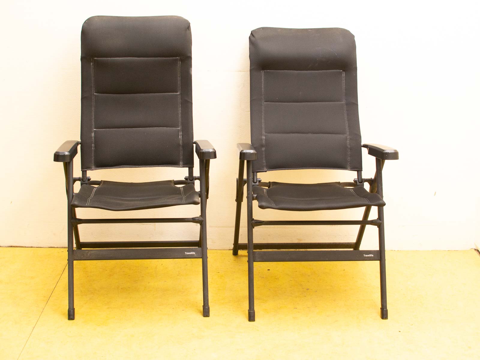 Stylish black folding chairs on a vibrant yellow floor, blending modern design with comfort.