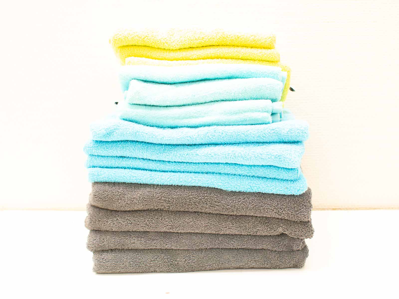 Colorful towel stack: bright yellow, soothing blues, and elegant gray for stylish bathrooms.