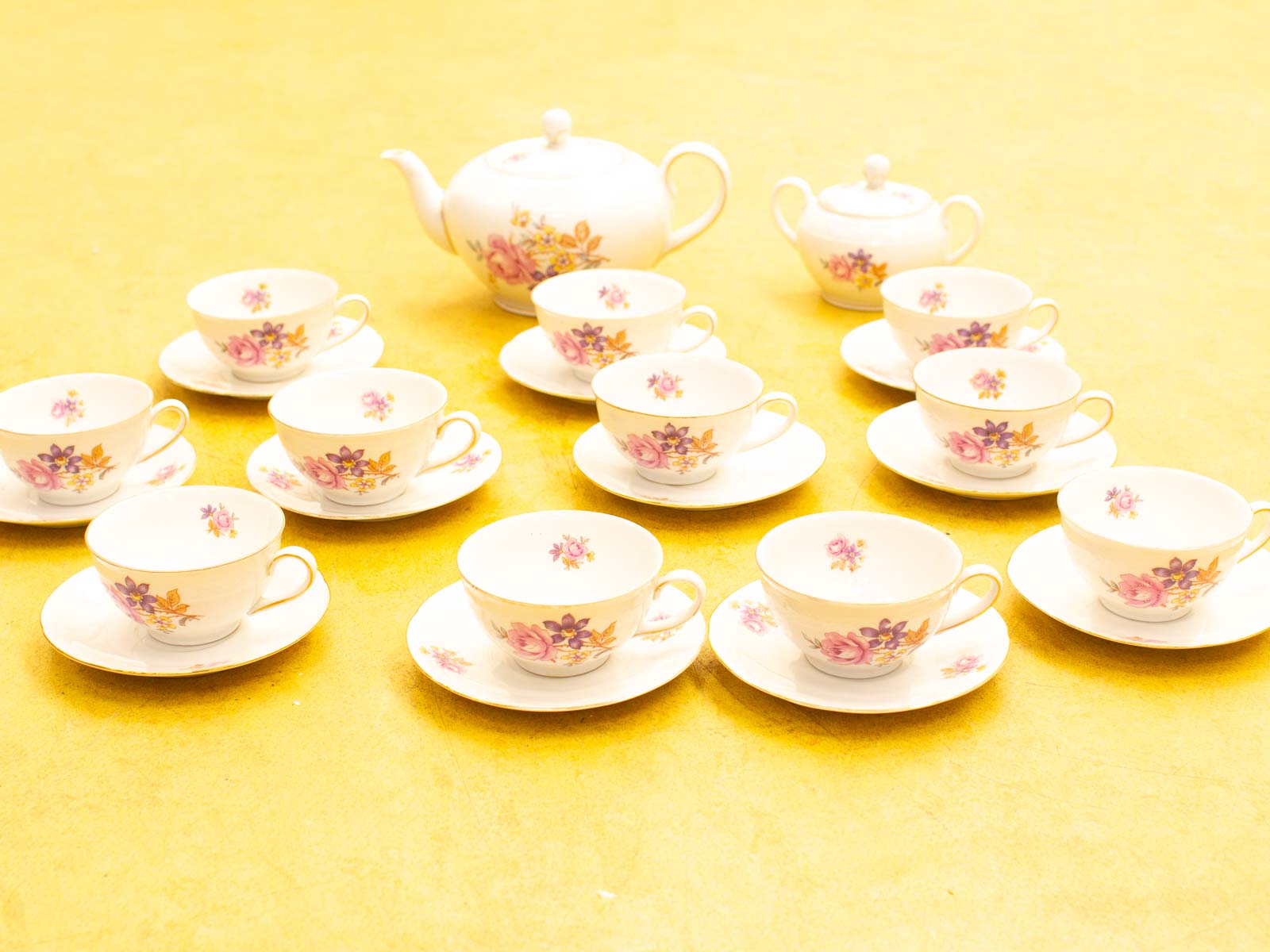 Elegant floral tea set on a bright yellow background, perfect for gatherings and tea parties.