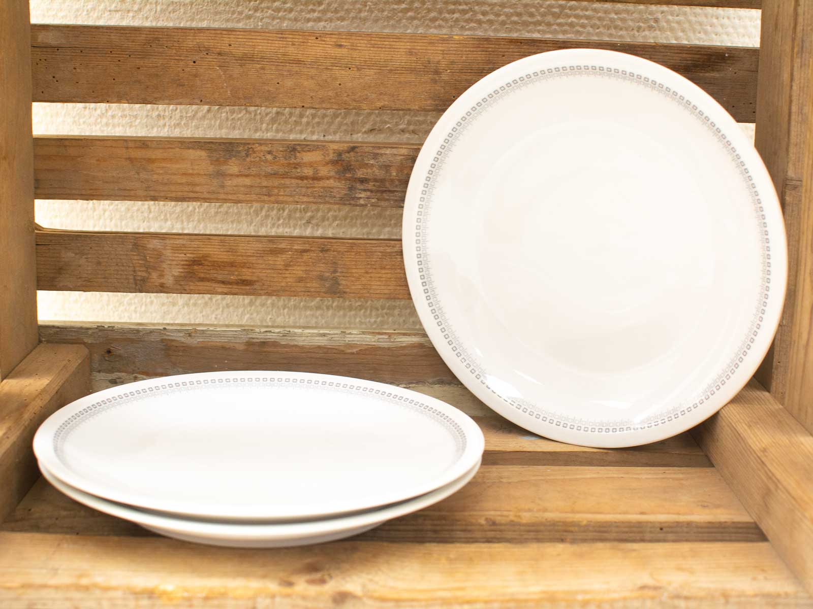 Elegant white plates on a rustic wooden shelf, perfect for vintage kitchen decor and gatherings.