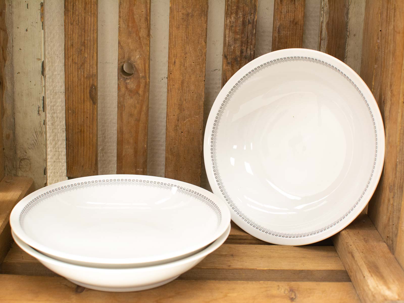 Elegant white plates on a rustic wooden shelf, combining charm and functionality for dining.