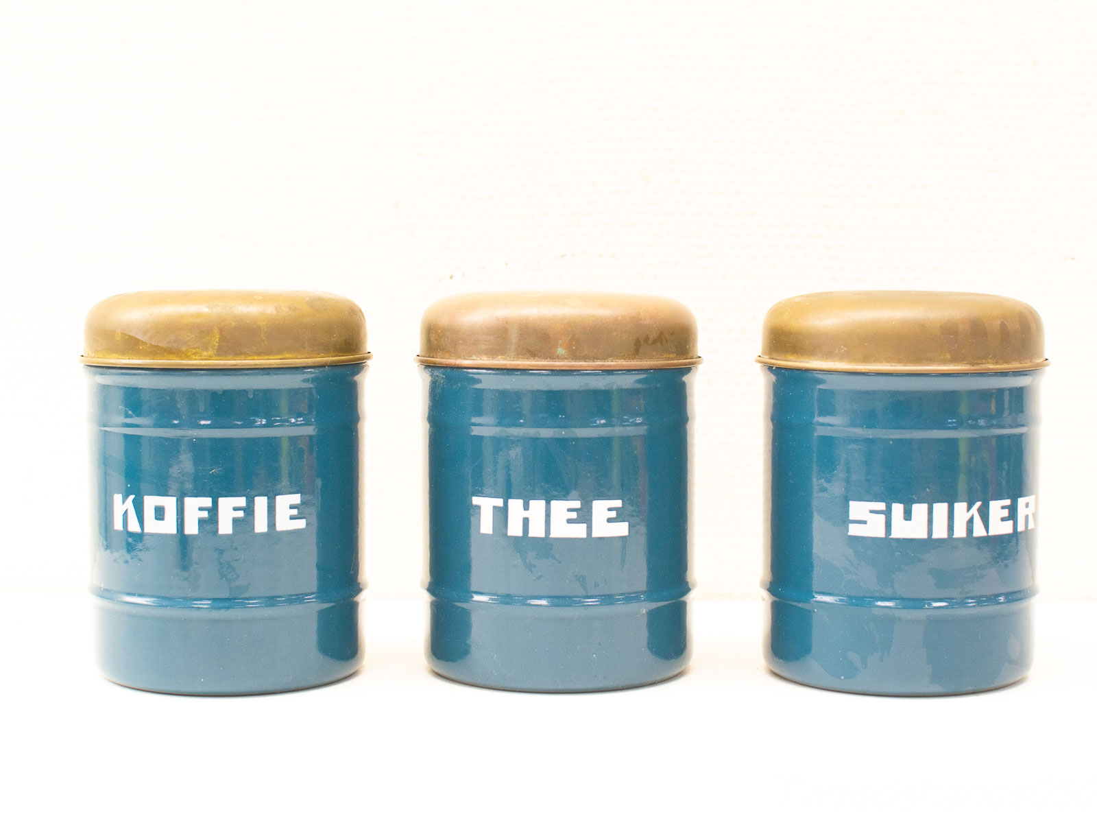 Charming vintage blue canisters for coffee, tea, and sugar with brass lids and white lettering.