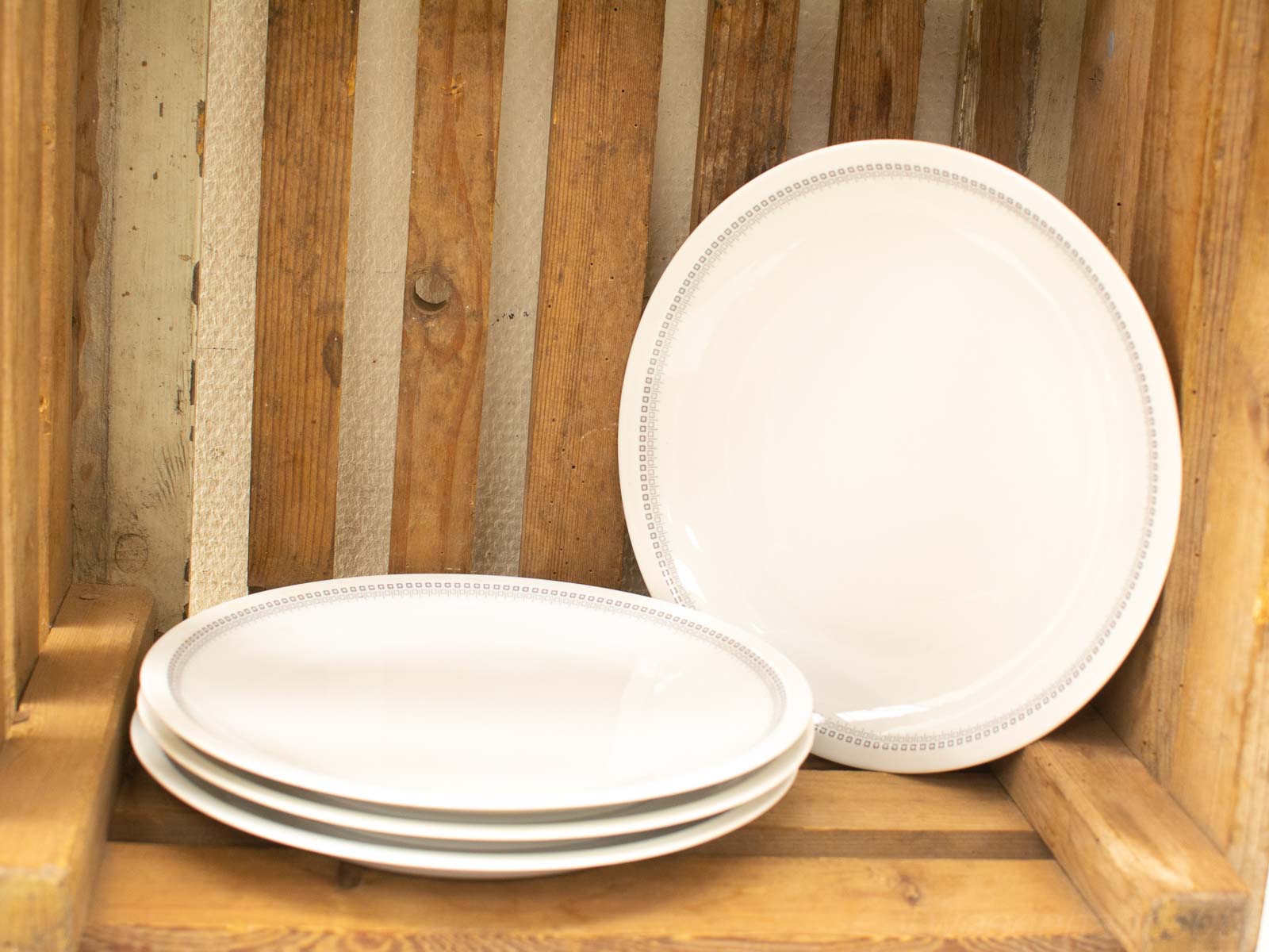 Elegant white plates in a rustic wooden crate, perfect for vintage dining settings.