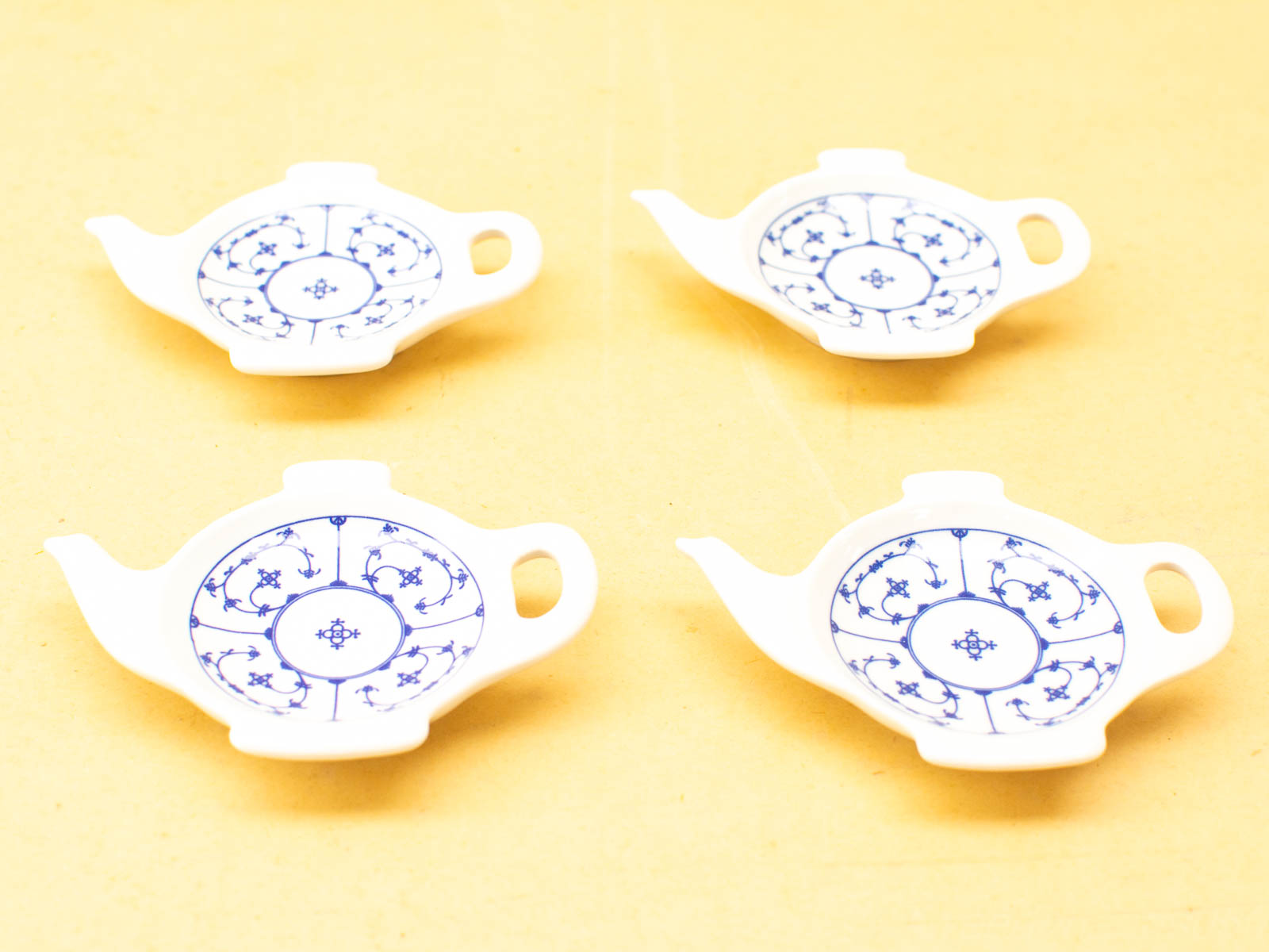 Charming set of four decorative teapot-shaped porcelain plates with intricate blue floral designs.