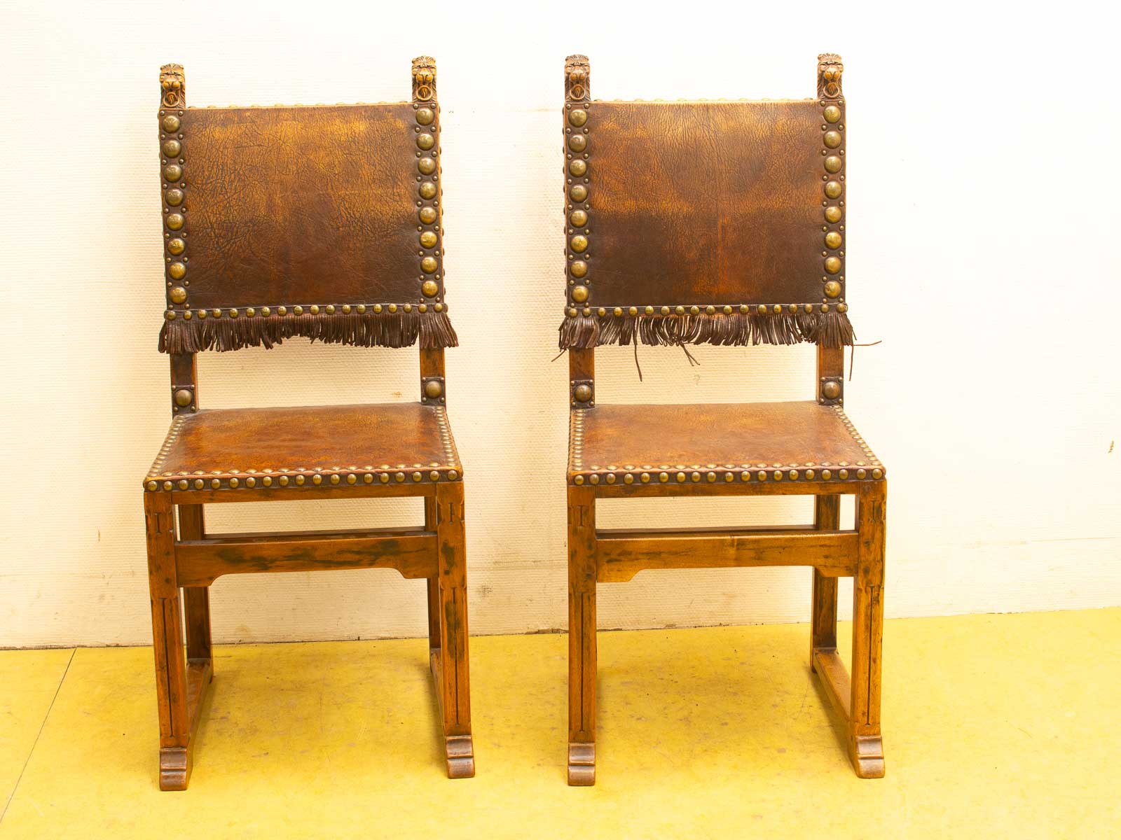 Rustic wooden chairs with luxurious leather upholstery and elegant brass accents for vintage decor.