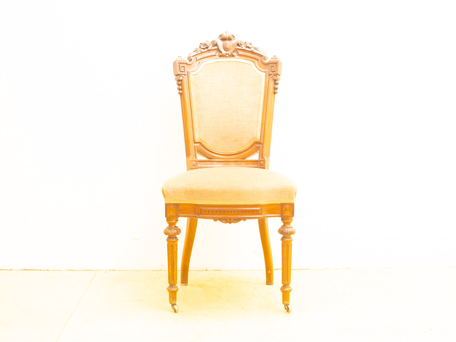 Elegant vintage wooden chair with intricate carvings and curved legs, upholstered in soft beige fabric.