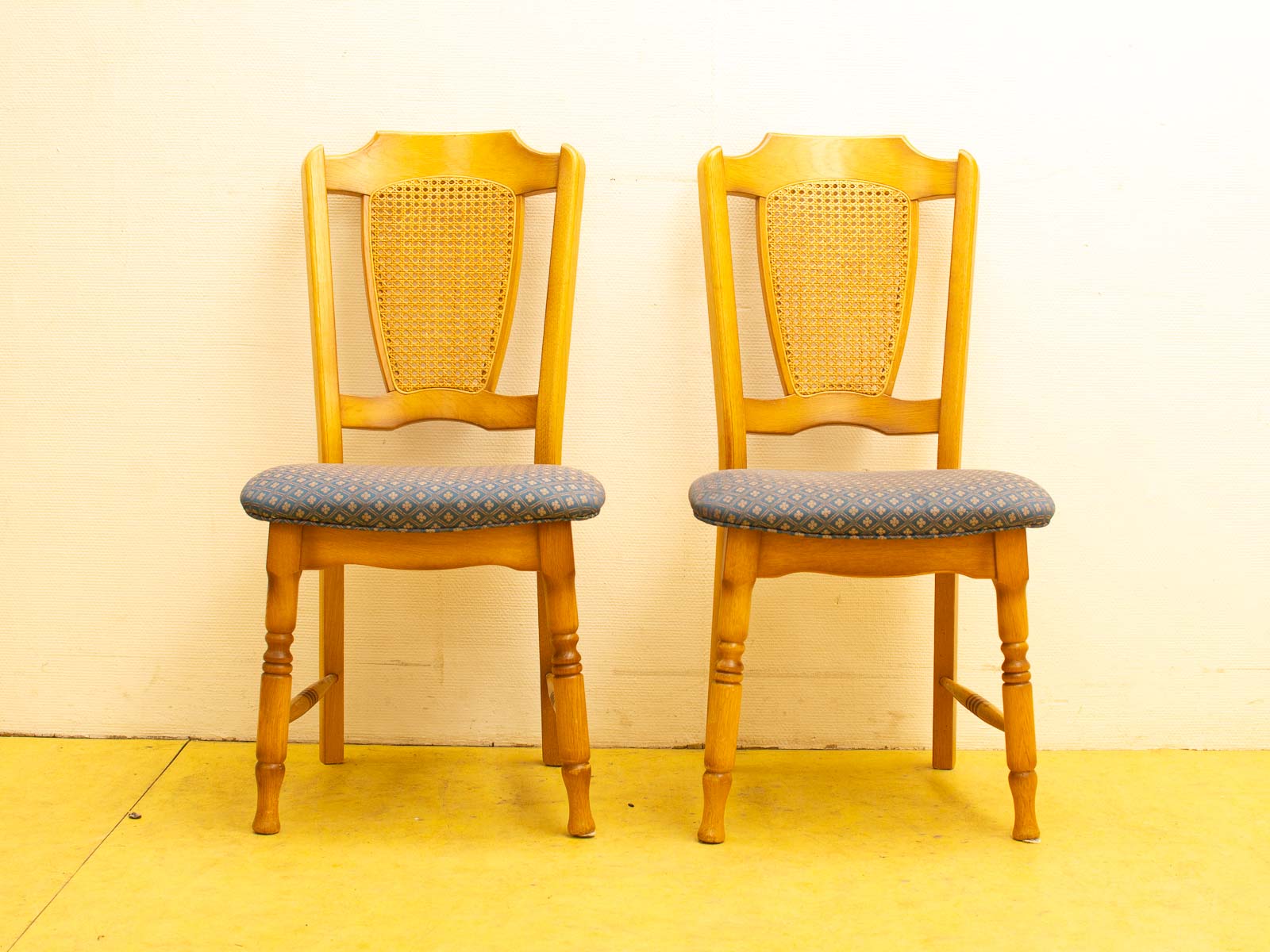 Elegant wooden chairs with blue geometric upholstery, perfect for cozy dining or café settings.