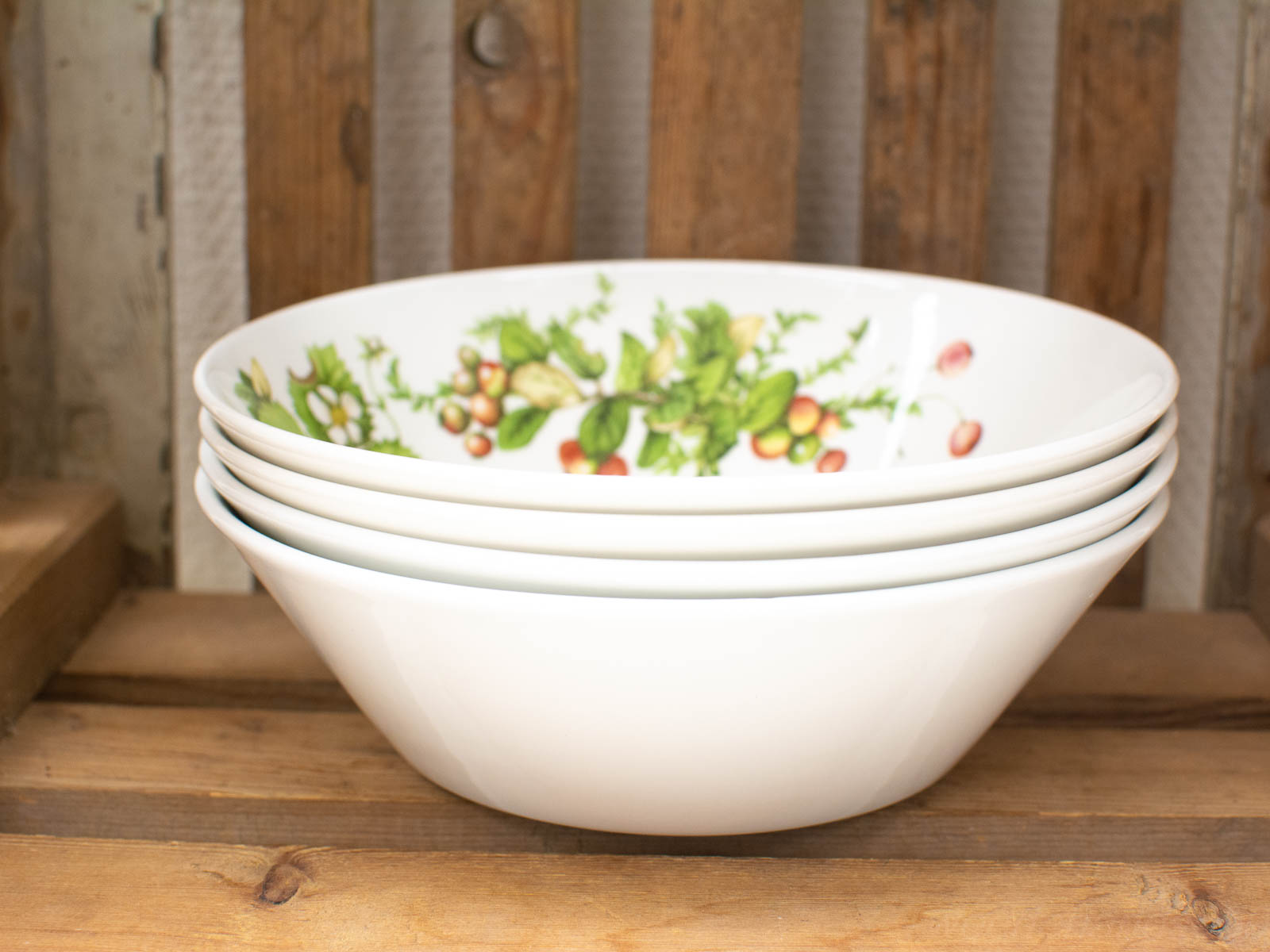 Elegant white serving bowls with fruit design against rustic wood, perfect for dining or decor.