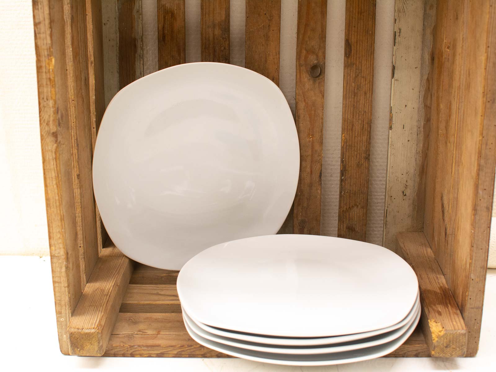 Rustic wooden crate with elegant white plates, blending charm and modern sophistication for stylish storage.