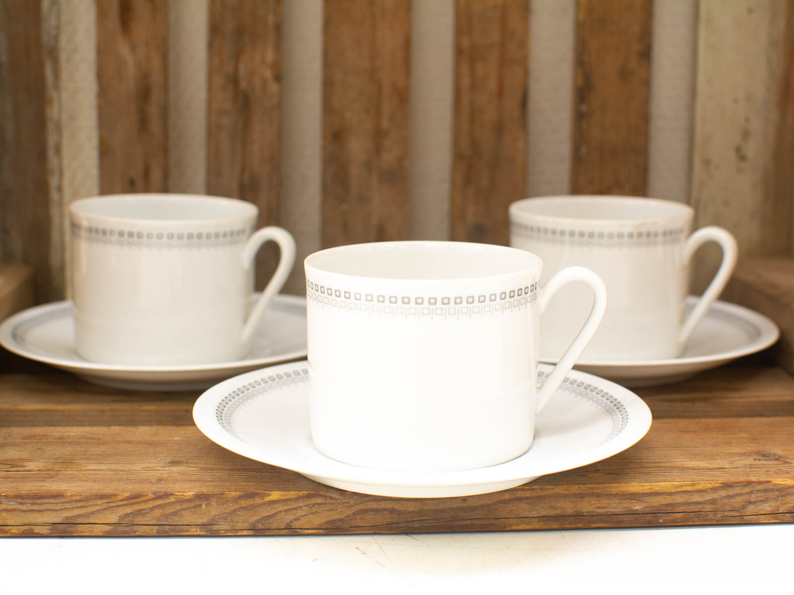 Elegant white porcelain cups and saucers on a rustic wooden table, perfect for cozy gatherings.