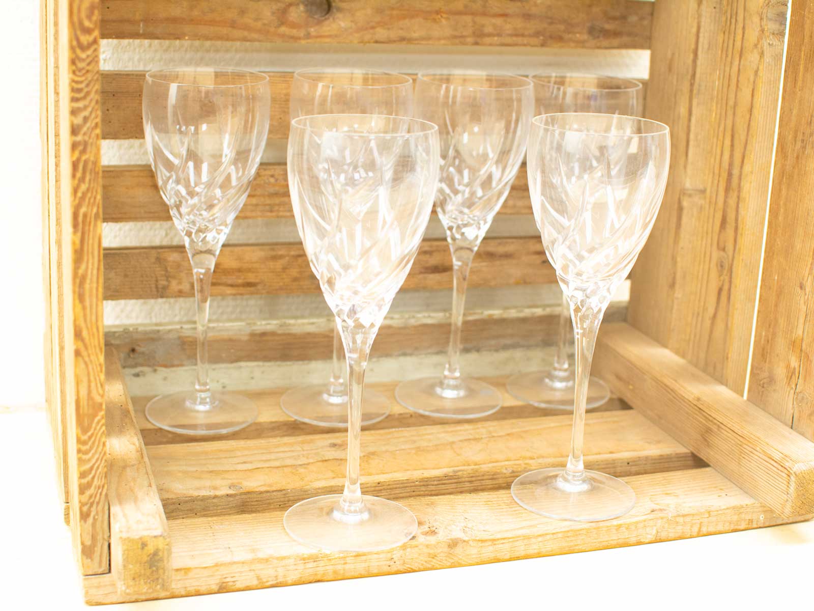 Elegant crystal wine glasses in a rustic wooden crate, perfect for special occasions and dining.