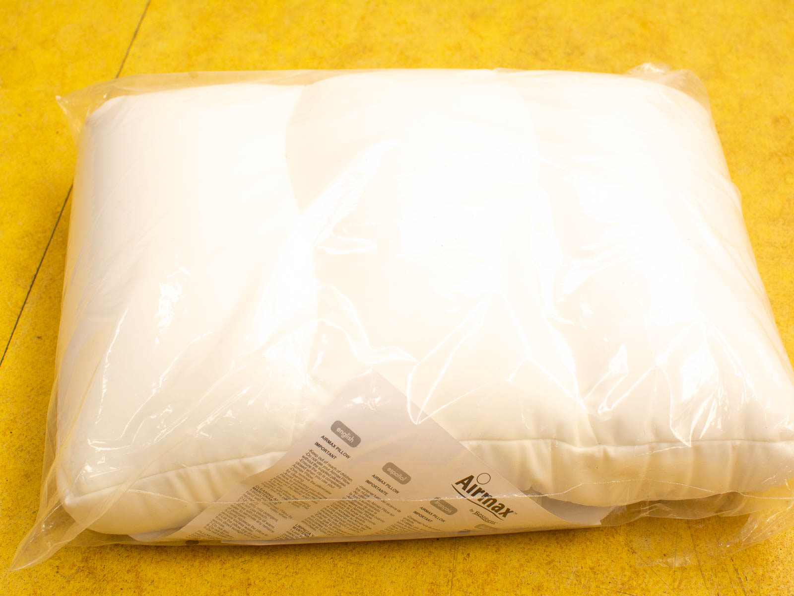 Airmax pillow in clear packaging on bright yellow surface, designed for ultimate comfort.