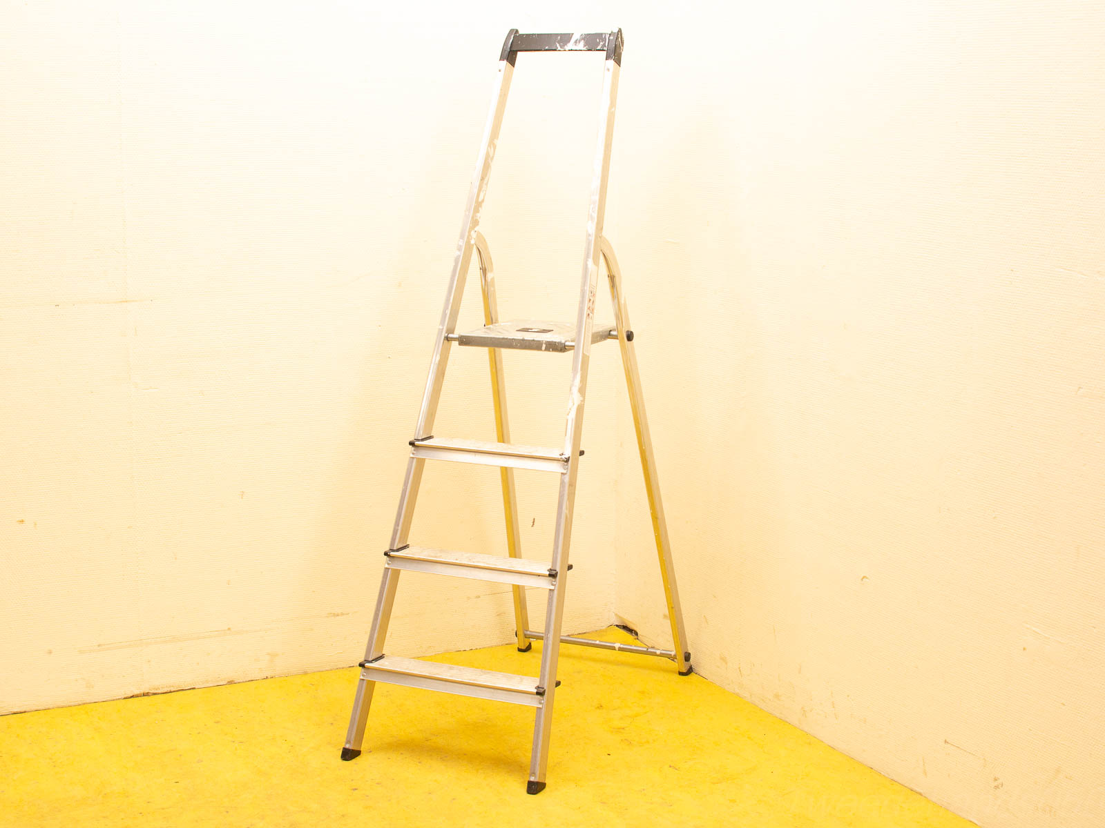 Stylish four-step aluminum ladder with paint splatters, ideal for DIY projects and practical use.