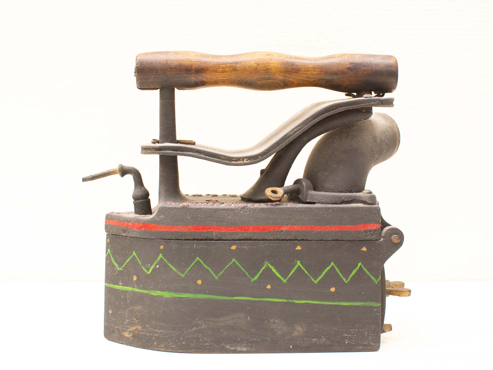 Antique iron with wooden handle and decorative patterns, showcasing vintage charm and functionality.