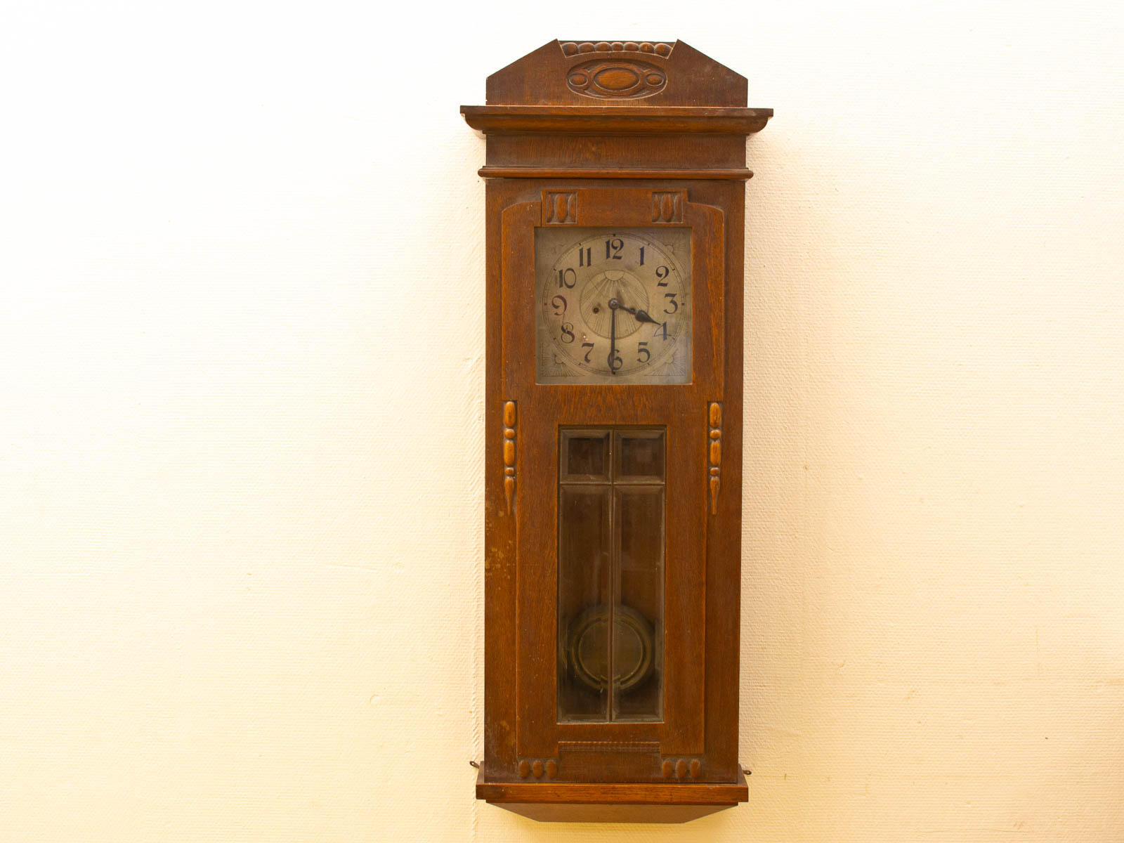 Vintage wooden wall clock with ornate details and brass pendulum, adding timeless elegance to any space.