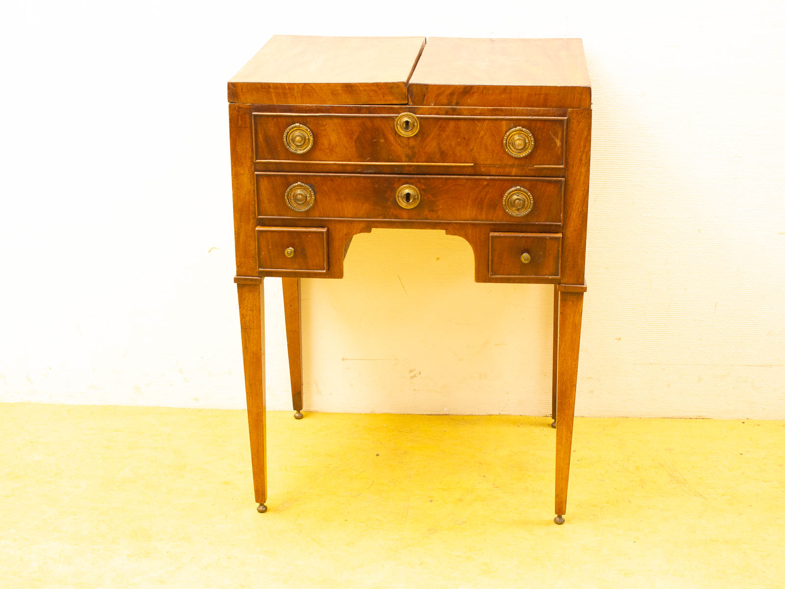 Elegant neoclassical wooden table with brass knobs and tapered legs, perfect for any space.