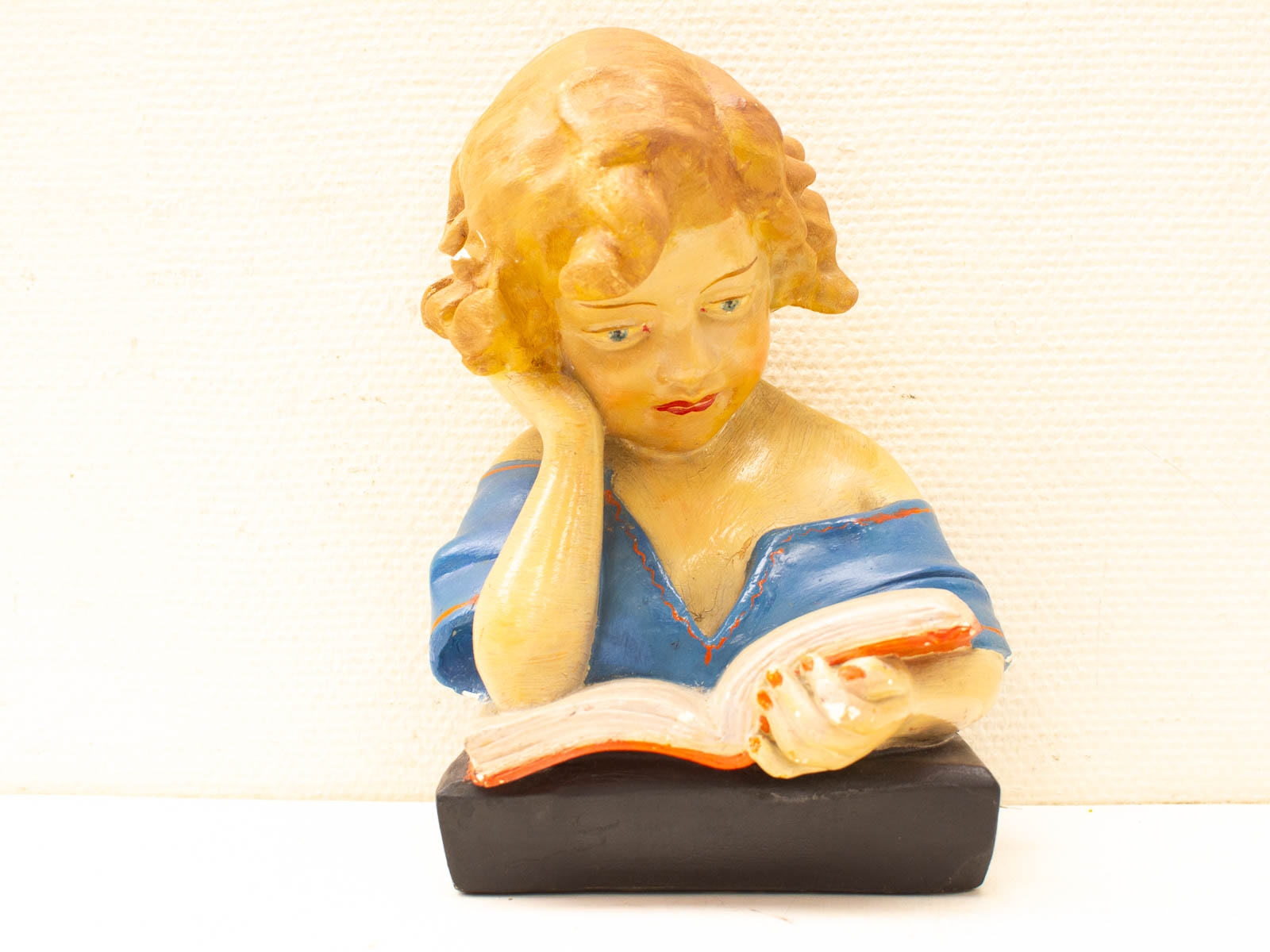 Charming vintage ceramic sculpture of a girl reading, capturing the joy of literature.