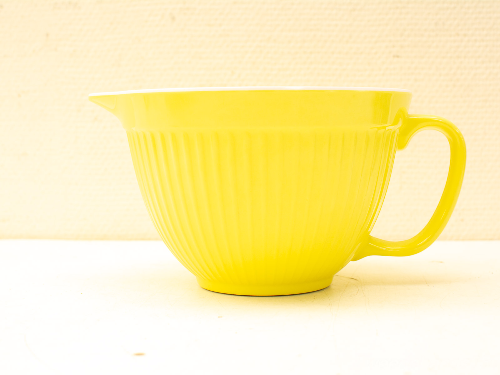 Cheerful yellow vintage mixing bowl with spout, textured grooves, and sturdy handle for practical use.