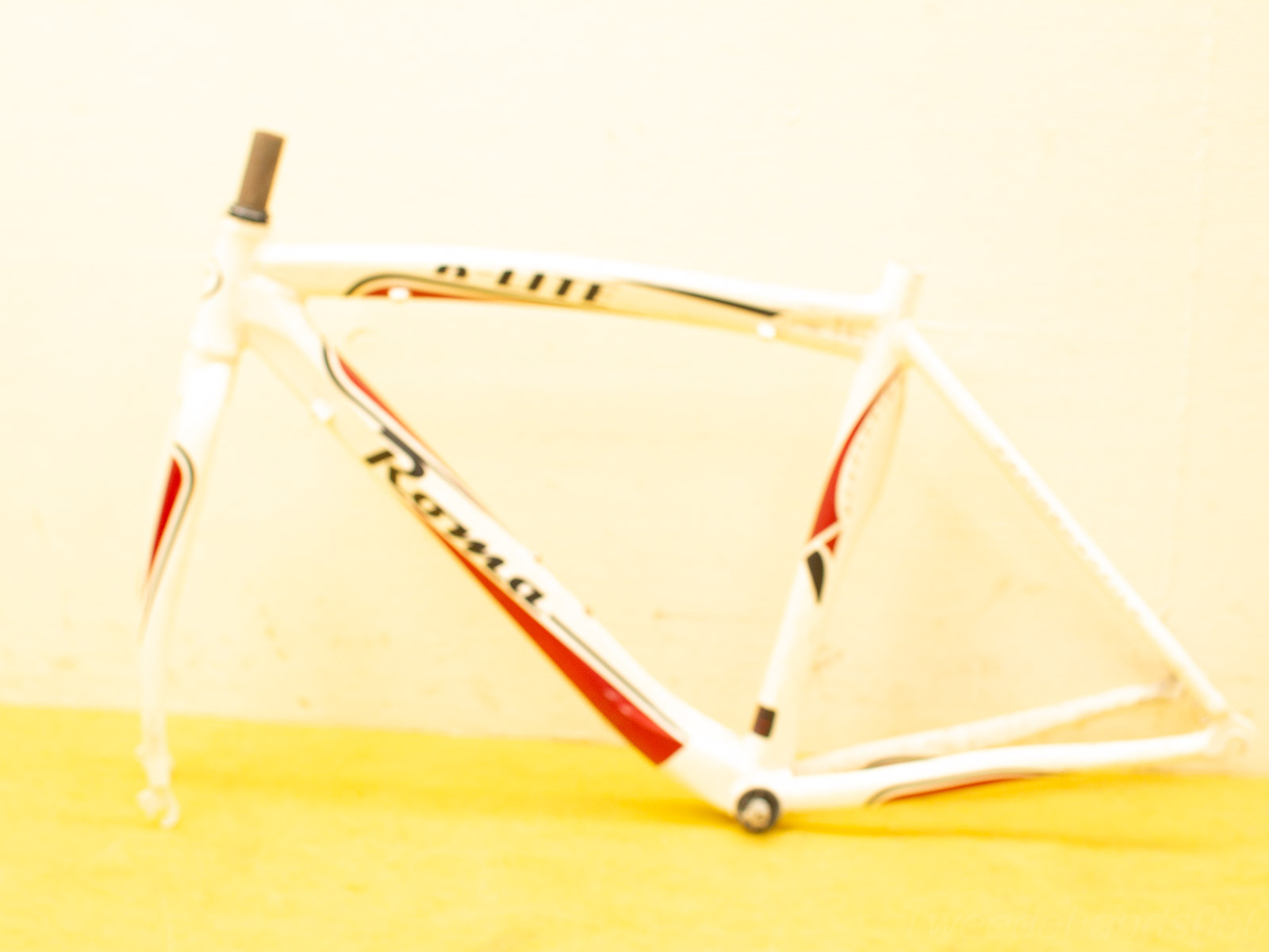 Aerodynamic vintage road bike frame in white, red, and black for speed and style.