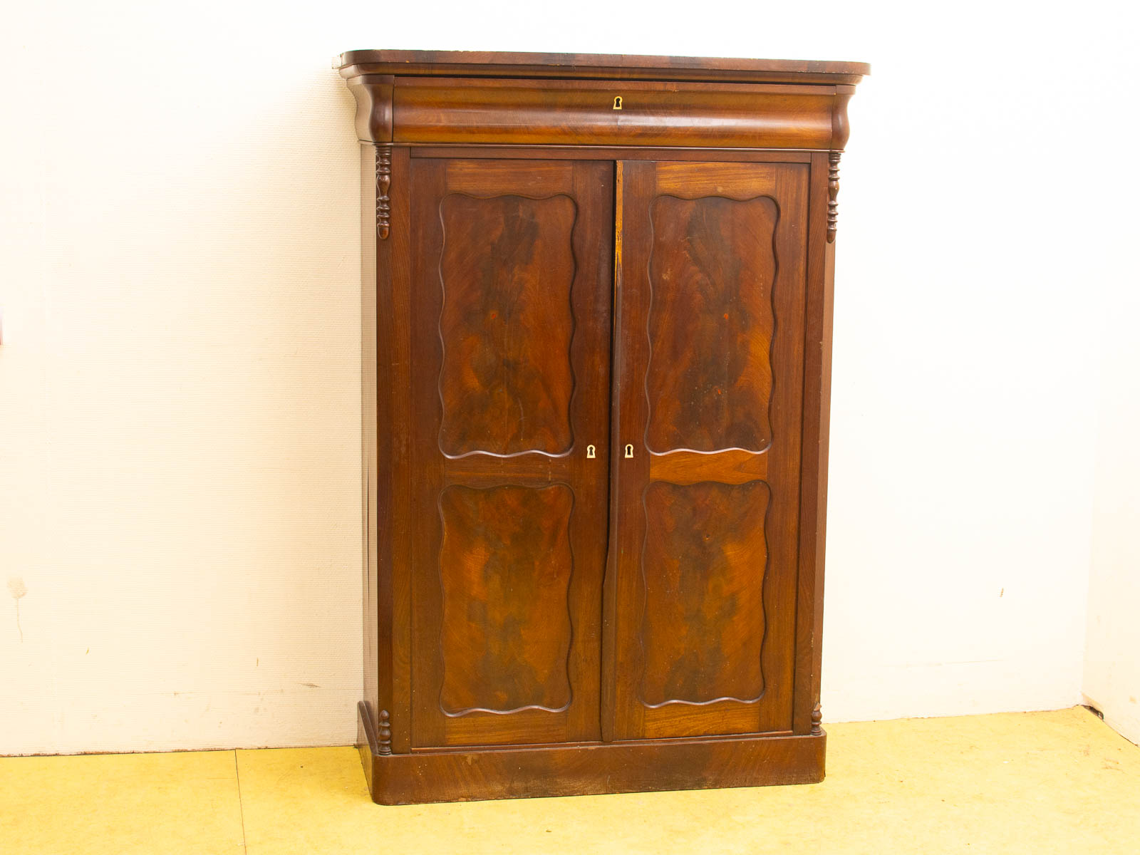 Elegant wooden cabinet with rounded edges, wavy panel doors, and artisanal details for sophisticated storage.