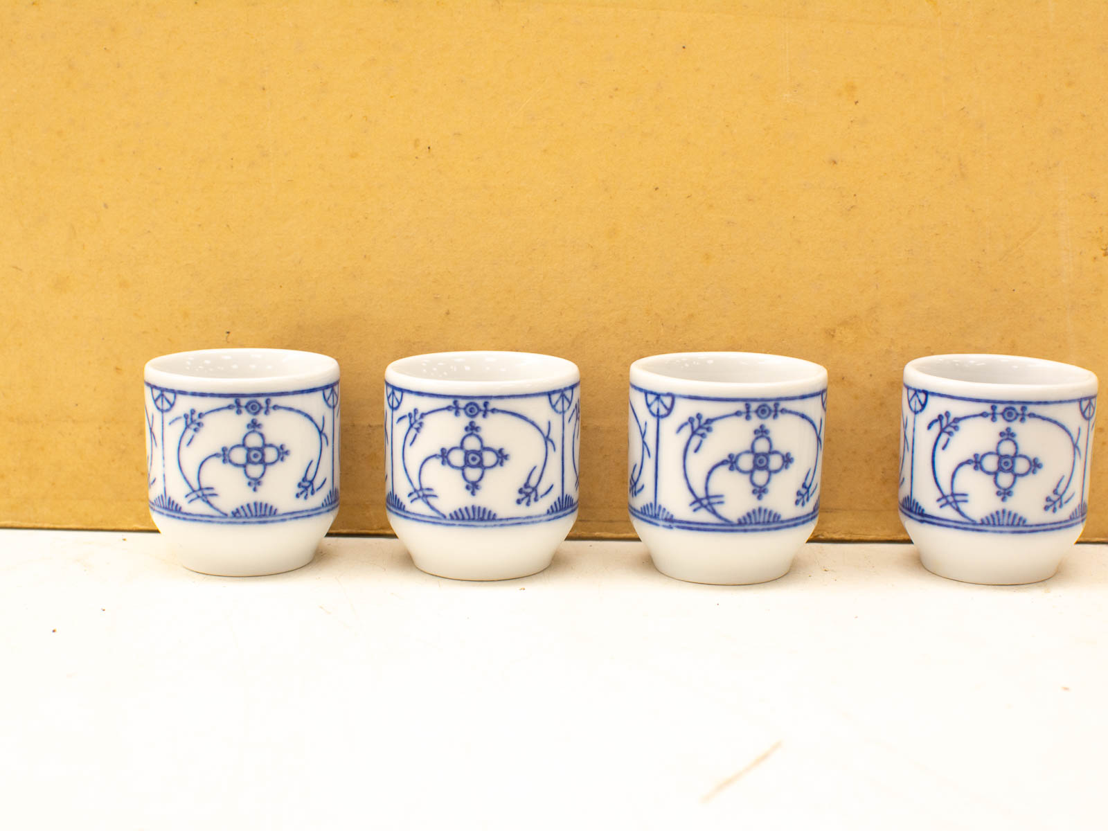 Elegant set of four blue-patterned porcelain cups on a neutral background. Perfect for decor or drinks.