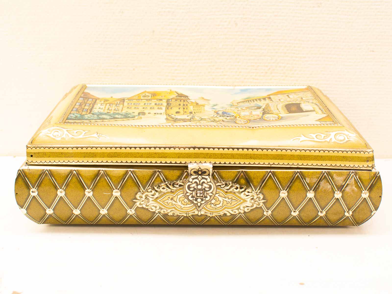 Antique decorative box with painted lid, intricate design, and ornate clasp for elegant storage.