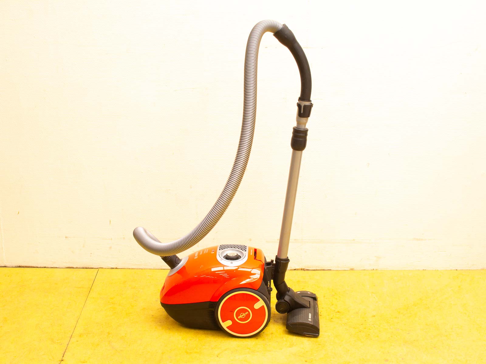 Compact red canister vacuum cleaner with flexible hose for efficient home cleaning.