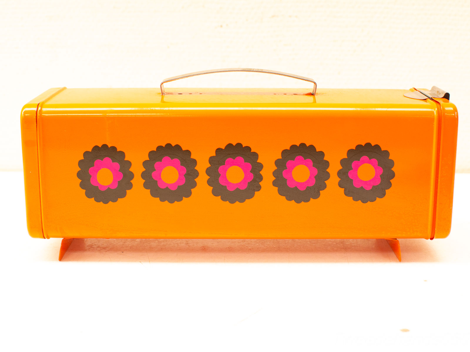 Charming vintage orange lunchbox with vibrant floral designs, perfect for collectors and decor.